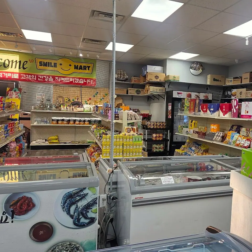 Rows of chest freezers in front of snack shelves, under the Welcome to SMILE MART banner