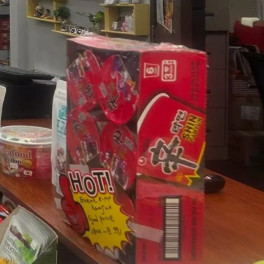 A case of Shin Ramyun with a hand-written HOT! sign on the counter